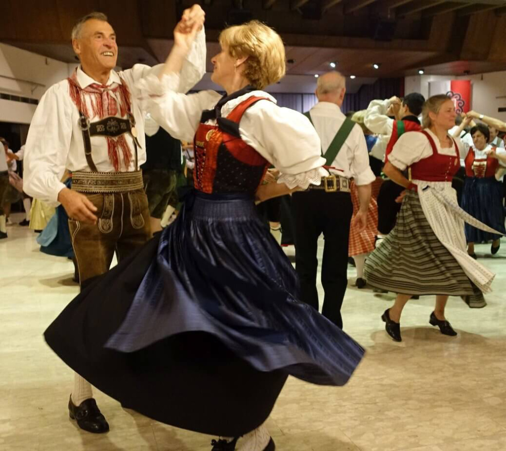 Paare in Tracht tanzen fröhlich bei einer Veranstaltung zu traditioneller Volksmusik aus Saalfelden