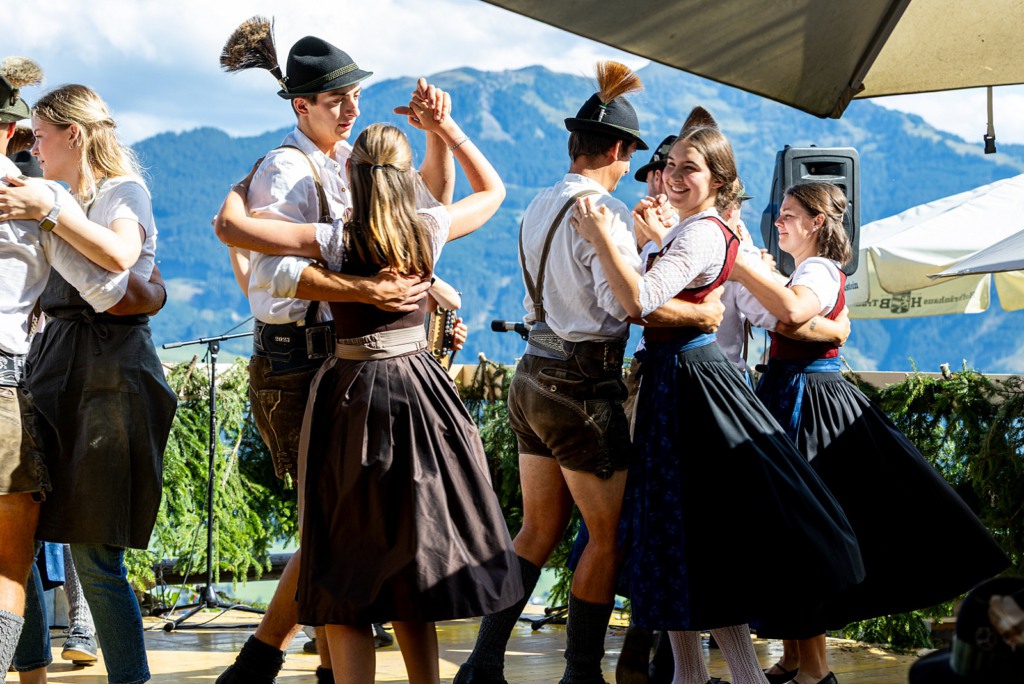 Tanzpaare in Tracht tanzen auf einer Bühne vor einer Bergkulisse